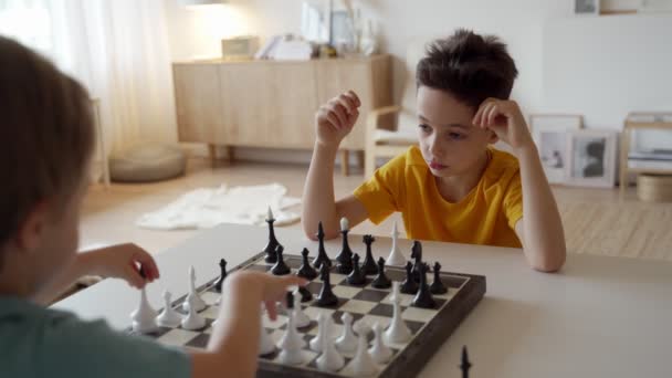 Two boy playing chess in light room. Two brothers playing chess. — Stock Video