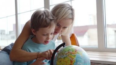 Beyaz elbise çekici bir anası onu genç oğlu dünya ülkelerinin göstermek için bir küre kullanır.