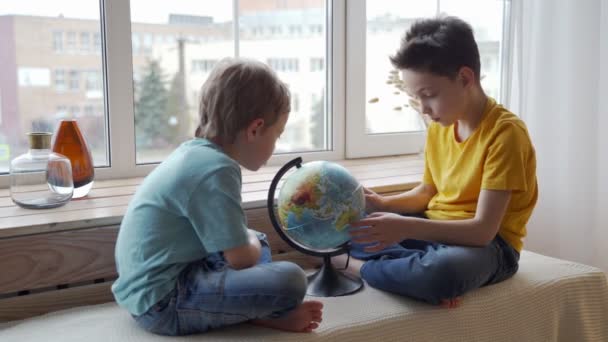 Два мальчика изучают географию Земли с помощью глобуса . — стоковое видео