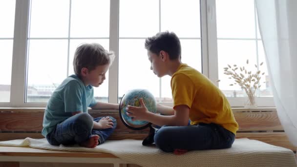 Twee jongens studeren de Geografie van de aarde met een globe. — Stockvideo