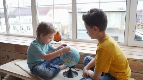 Dos chicos estudiando la geografía de la tierra con un globo . — Vídeos de Stock