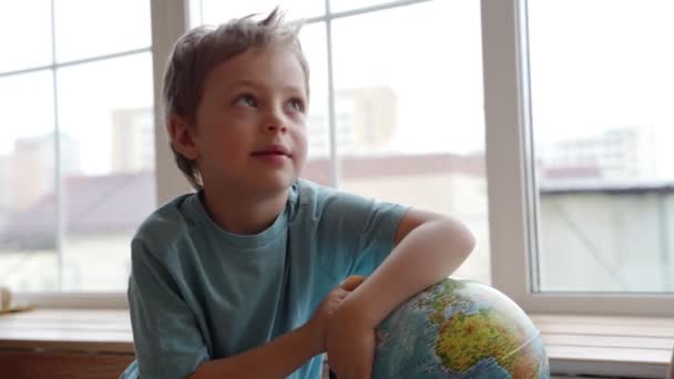 An attractive mother of caucasian ethnicity uses a globe to show her young son the countries of the world. — Stock Video