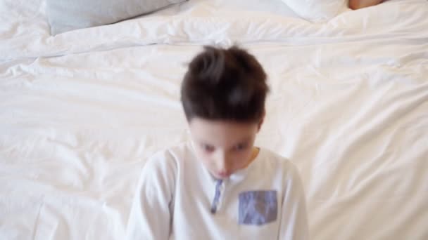 Menino brincando, adormece na cama antes de dormir — Vídeo de Stock