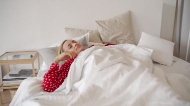 Günaydın. Oynak sevimli genç kadın yatakta beyaz örtüsü altında yalan, germe, silah yükselterek, gün için büyük planları olan Kızıl saçlı. Sevimli kız yatak odasında, tembellik yapmak mutlu bir şekilde gülümseyerek
