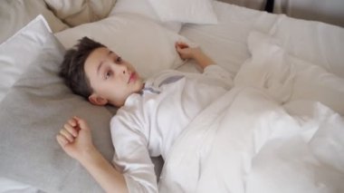 Sevimli genç çocuk sabah uyanma. Yatakta uzanan çocuk