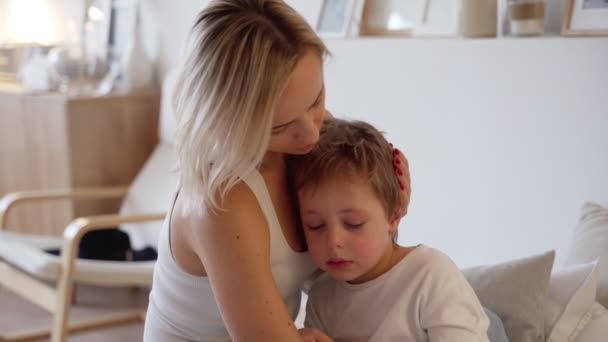 Junge Mutter umarmt einen weinenden Jungen im Schlafzimmer — Stockvideo