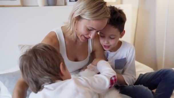 Glückliches Wochenende - junge Mutter mit glücklichen Kindern beim Spielen im Bett und Ingwer weiße Katze auf dem Bett liegend in echtem Interieur — Stockvideo