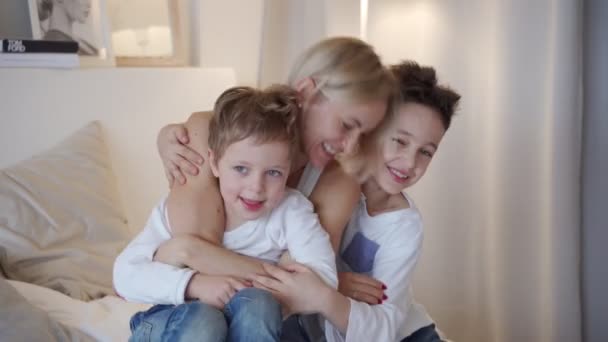 Gelukkige familie - moeder met twee zoons, knuffelen in bed — Stockvideo