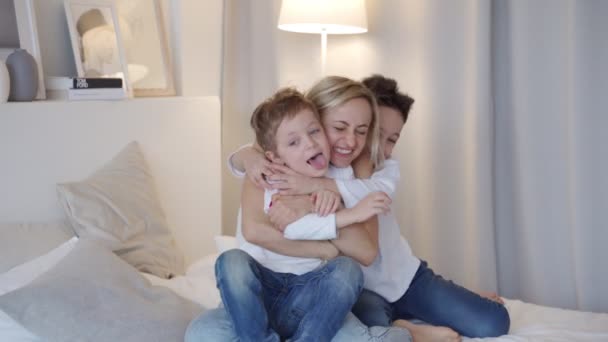 Famiglia felice - madre con due figli che si abbracciano a letto — Video Stock