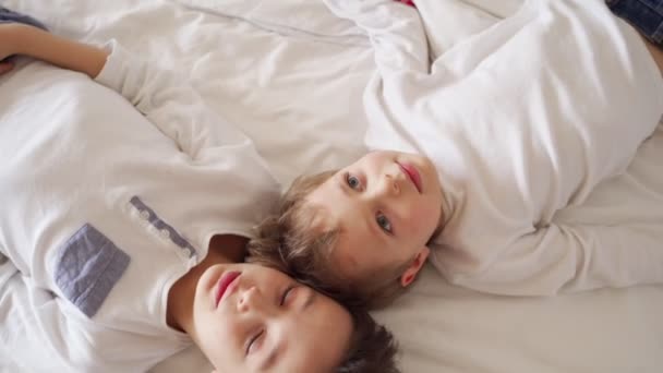 Два мальчика лежат в кровати, разговаривают и смотрят в потолок — стоковое видео