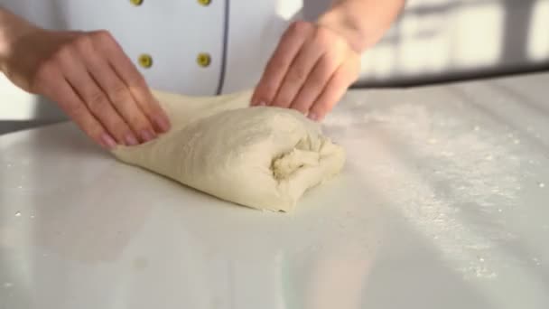 Panadero amasar la masa en harina sobre la mesa. Primer plano de las manos femeninas que trabajan con masa — Vídeo de stock