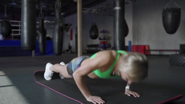 Atlética hermosa mujer does push-ups como parte de su cruz fitness, levantamiento de pesas gimnasio entrenamiento rutina — Vídeos de Stock