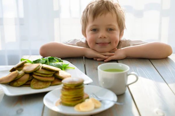 Lindo niño de cinco años con pila de tortitas de espinacas — Foto de Stock