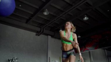 Güçlü olan kadın mükemmel fitness vücut içinde spor salonunda sağlık topu ile egzersiz. CrossFit eğitim yaparken kız. Ağır çekim. Yakın çekim