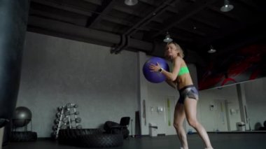 Güçlü olan kadın mükemmel fitness vücut içinde spor salonunda sağlık topu ile egzersiz. CrossFit eğitim yaparken kız. Ağır çekim. Yakın çekim