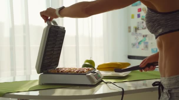 Una donna sportiva che cucina deliziose cialde ai mirtilli belgi per colazione al mattino in cucina — Video Stock