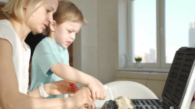 Mutfakta waffle pişirme genç kadın ve sevimli çocuk ona yardımcı olur. Sabah erken saatlerde famaly pişirme kahvaltı