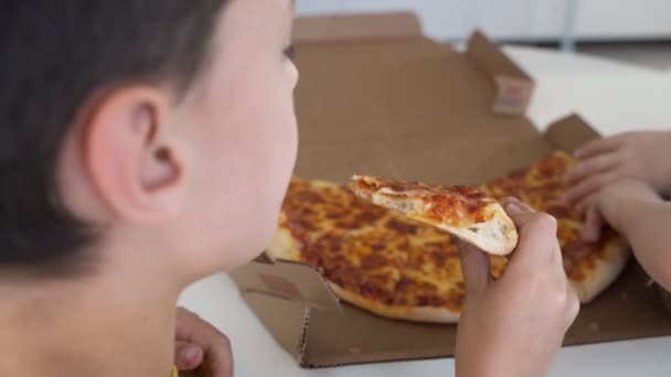 Twee kleine Kaukasische jongens eten pizza thuis. Dag licht — Stockvideo