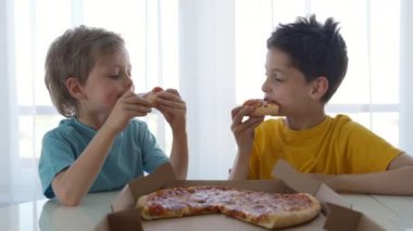 Evde pizza yiyen iki beyaz çocuk. Gün ışığı