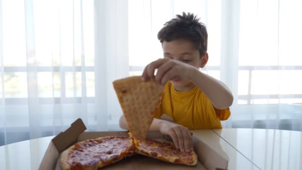 Twee kleine Kaukasische jongens eten pizza thuis. Dag licht — Stockvideo