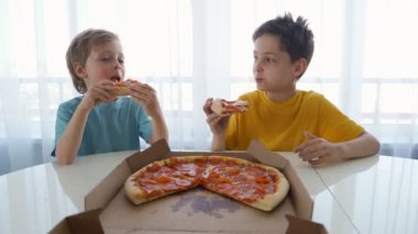 Evde pizza yiyen iki beyaz çocuk. Gün ışığı