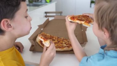 Evde pizza yiyen iki beyaz çocuk. Gün ışığı