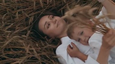 Genç anne ve çocuk oğlu küçük sevimli çocuk ile birlikte güzel kadın eğlenmek sarılma bir buğday tarlasında yalan.