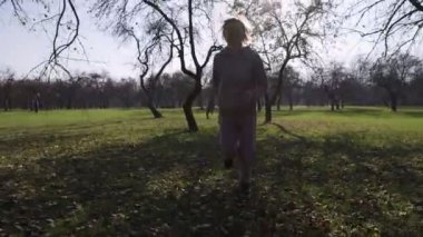 Çocuklu bir anne parkta koşuşturuyor, birbirlerinin etrafında koşuyor ve eğleniyor. Çocuk anne ördekleri ve kurnazlığı yakalayamıyor.