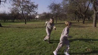 Çocuklu bir anne parkta koşuşturuyor, birbirlerinin etrafında koşuyor ve eğleniyor. Çocuk anne ördekleri ve kurnazlığı yakalayamıyor.