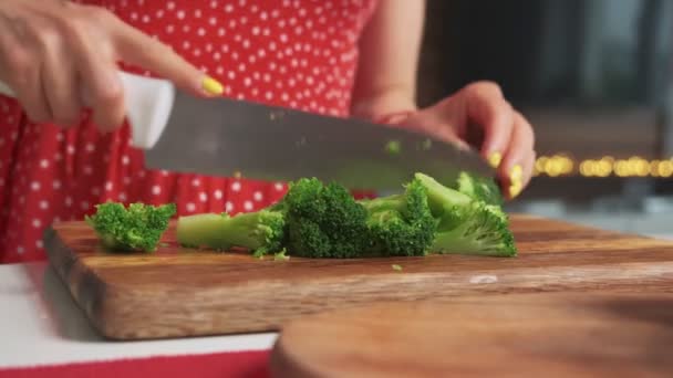 Close up shot of a woman cuting healthy vegetables on a wooden cutting board in a modern kitchen with a big knife — Stock Video