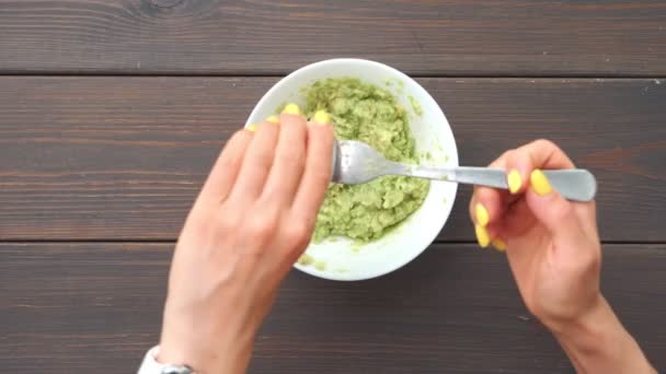 Avokadoyu çatalla kaseye sıkıştıran eller. Masa üstü görüntü. Sağlıklı yemek pişirme. — Stok video