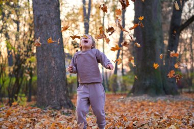 Sonbahar yapraklarında koşan küçük bir çocuk. Çal, ara sokak