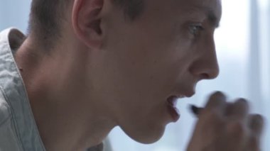 Genç adam ofiste dizüstü bilgisayarla çalışırken çikolata yiyor. Kapat.