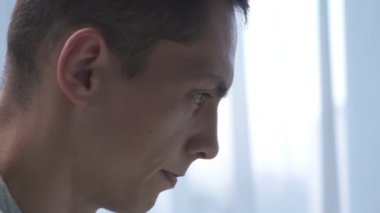 Genç adam ofiste dizüstü bilgisayarla çalışırken çikolata yiyor. Kapat.