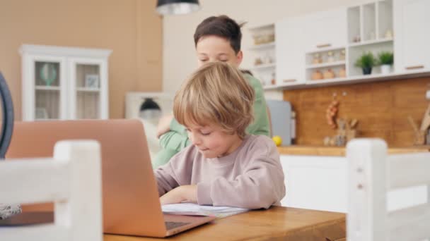 Due ragazzi fanno i compiti. Fratello maggiore aiuta il più giovane con i compiti I ragazzi stanno usando i computer per insegnare e spiegare i compiti. Agli amici con espressioni facciali e gesti felici — Video Stock