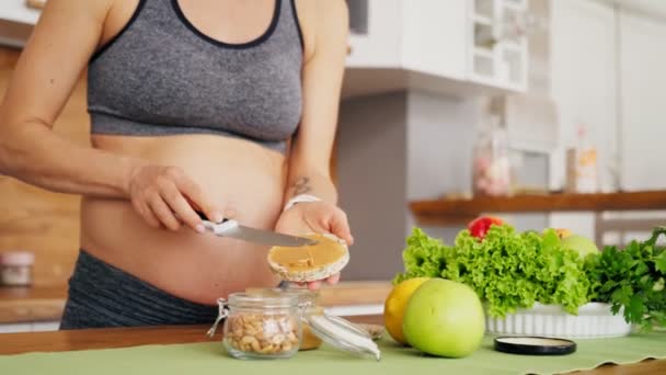Schwangere bereitet Sandwich mit Erdnussbutter und Reiswaffel zu. Ernährungslaunen schwangerer Frauen — Stockvideo