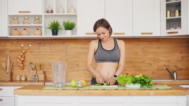 Mulher grávida preparando salada verde fresca na cozinha. Conceito de gravidez saudável — Vídeo de Stock