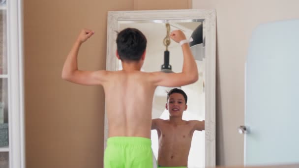 Atraktivní teenager s nahým trupem pózující na kameře a ukazující svaly v zrcadle. — Stock video