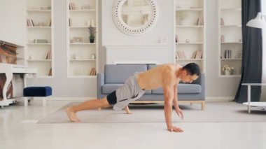 Güçlü, kaslı bir adam spor salonunda çalışıyor. Tek kolu yoğun duygularla şınav çekiyor. Kararlı fitness adamı daha güçlü olmaya odaklanmış.