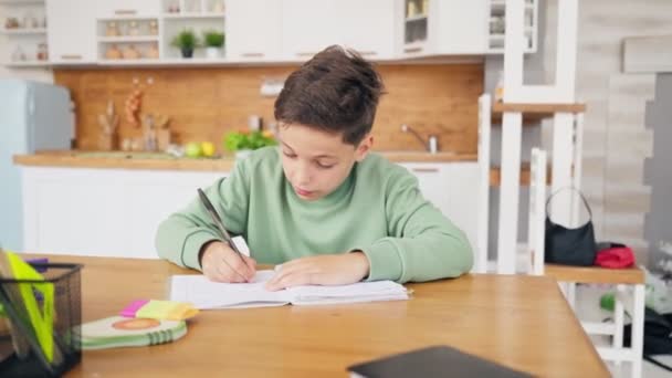 Chlapec v kuchyni dělá domácí úkoly a chatování s notebookem na stole. — Stock video