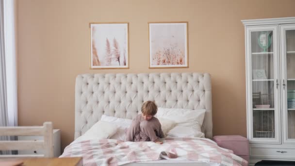 Blank jongen springen op bed hebben plezier lachen spelen grappig actief spel met schattig kind zoon in slaapkamer. — Stockvideo