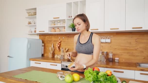 Mujer embarazada haciendo sándwich con mantequilla de maní y gofre de arroz. Los caprichos alimenticios de las mujeres embarazadas — Vídeos de Stock