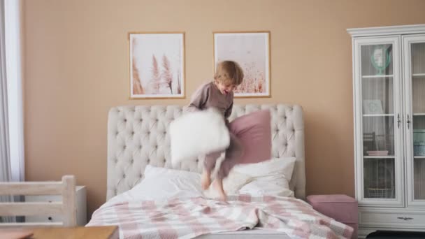 Caucásico chico saltando en la cama divirtiéndose riendo jugando divertido juego activo con lindo niño hijo en el dormitorio. — Vídeos de Stock