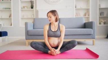 Formda Hamile Kız, Spor Egzersizleri yapıyor. Oturma odasının zemininde, Yoga Mat 'ta oturuyor..