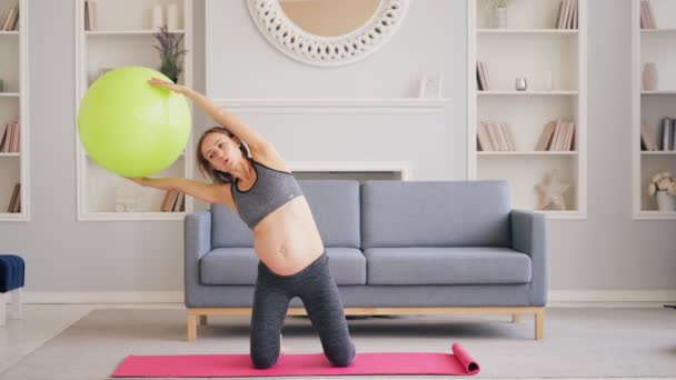 Ciężarna kobieta Ćwiczenia z Pilates Ball w salonie — Wideo stockowe