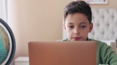 COVID-19 karantinası sırasında küçük bir çocuk odasından online okul derslerine katılıyor.
