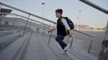 Sırt çantalı öğrenci güneşli bir günde ders almak için üst kata çıktı. Yan görünüm