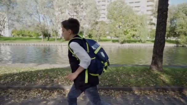 Menino caucasiano de 10 anos está atrasado para as aulas na escola. O rapaz está a correr a toda a velocidade. De volta à escola — Vídeo de Stock