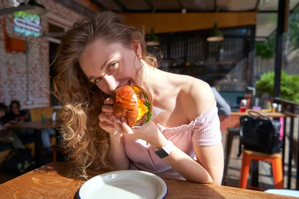 Belle femme caucasienne mangeant un délicieux hamburger au soleil jour — Photo