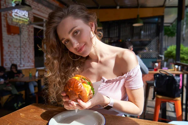 Krásná kavkazská žena jí lahodný burger za slunečného dne — Stock fotografie